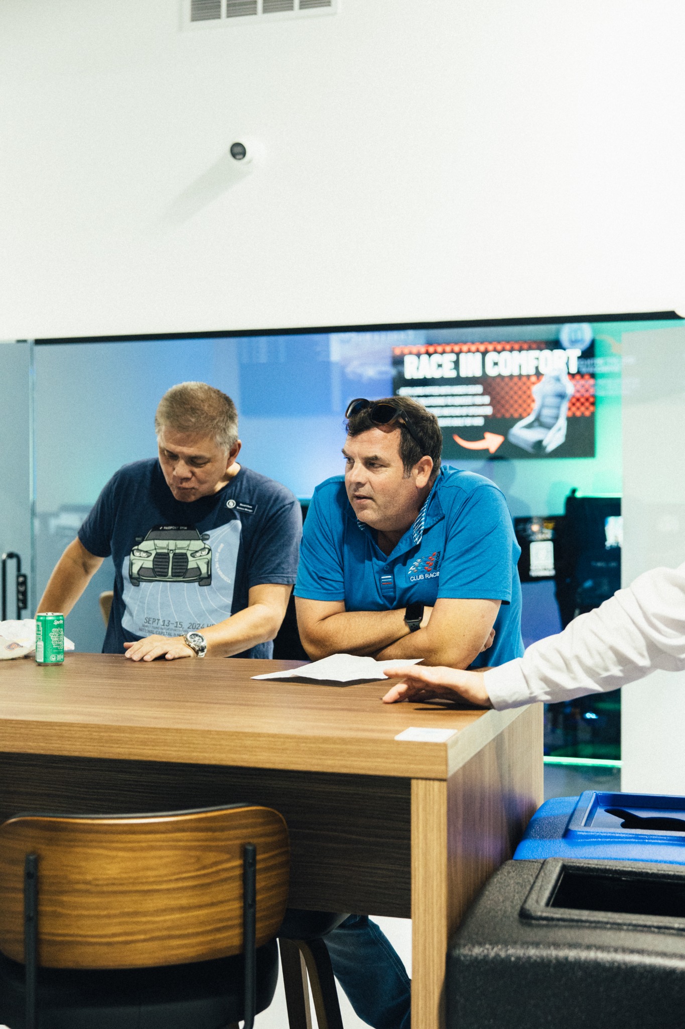 Two members seated at a table inside SIM1 Racing during the NJ BMW CCA meeting.