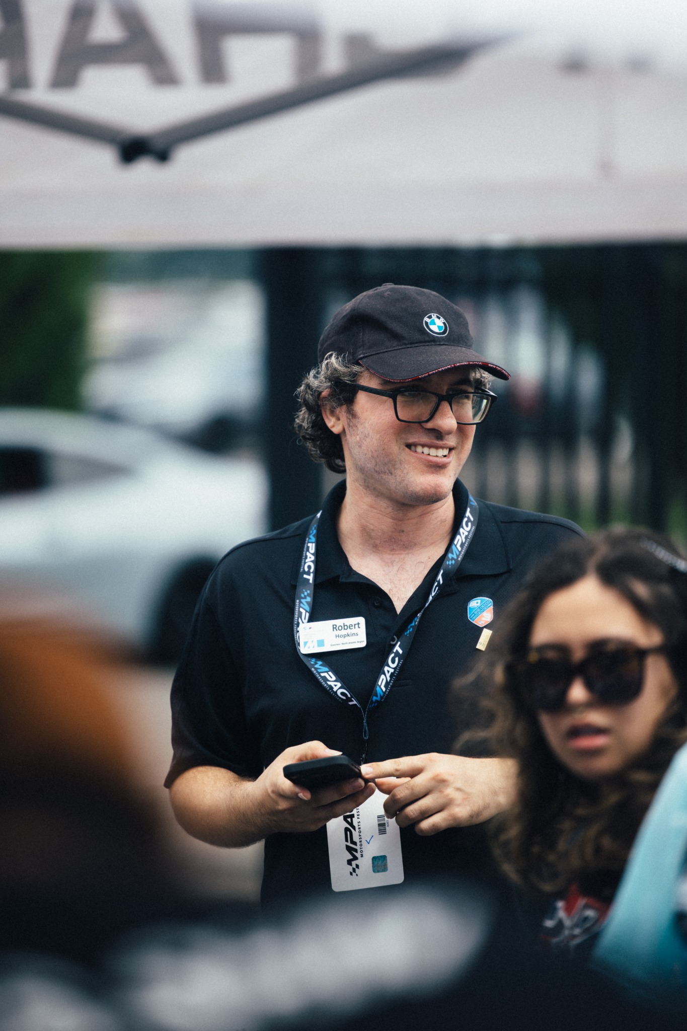 CCA team member wearing an event badge among attendees and BMWs.