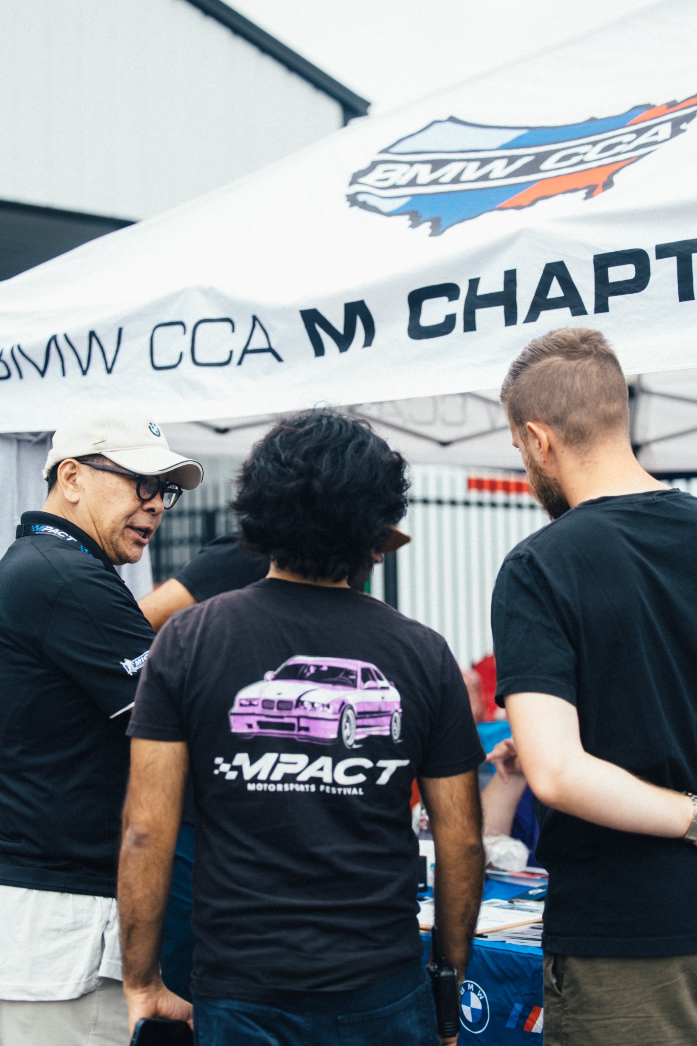 Enthusiasts and volunteers talking beneath the BMW CCA M Chapter banner.